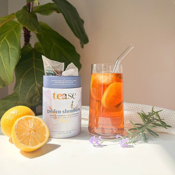 Tease Wellness Golden Slumbers organic tea blend tube with loose tea, fresh lemon, and glass tea with lemon slices and glass .