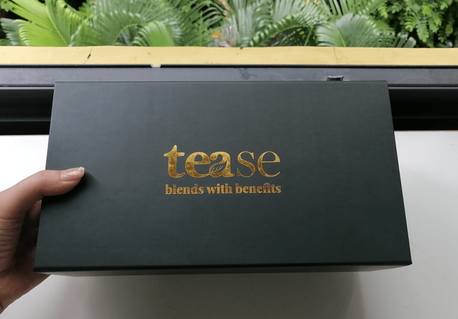 Tease Wellness Gift Box in matte black with gold logo and tagline "blends with benefits" on the lid.