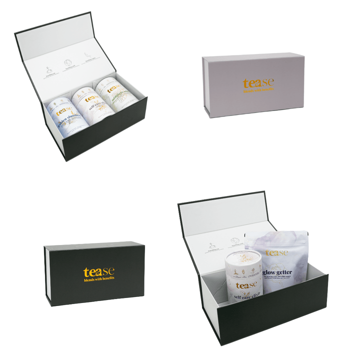 Tease Wellness gift box with branded packaging containing tea blends in white containers and foil pouches, sleek black and.