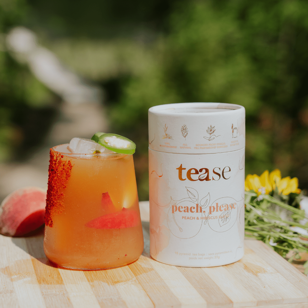 Tease Wellness Peach, Please tea blend in white tube with peach and ginger flavor next to iced peach tea with chili salt rim.