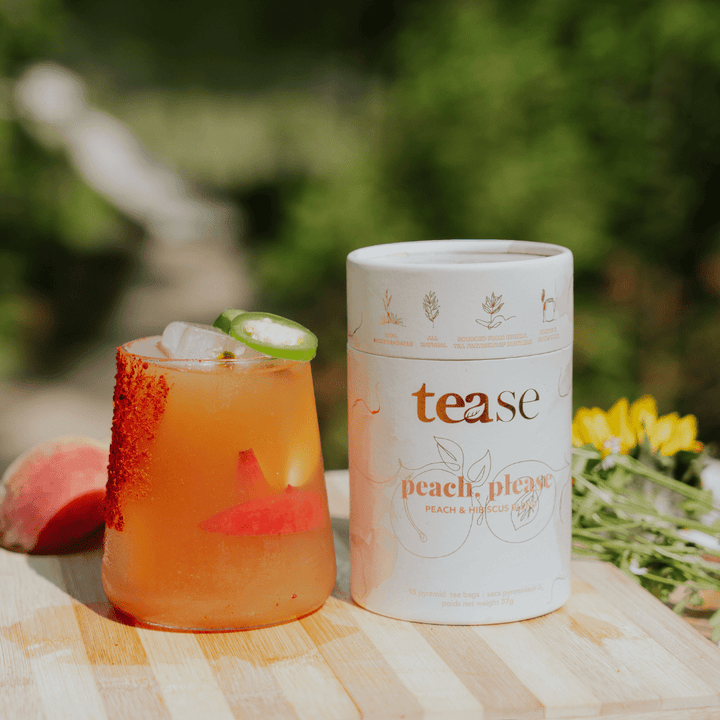 Tease Wellness Peach, Please tea blend in white tube with peach and ginger flavor next to iced peach tea with chili salt rim.