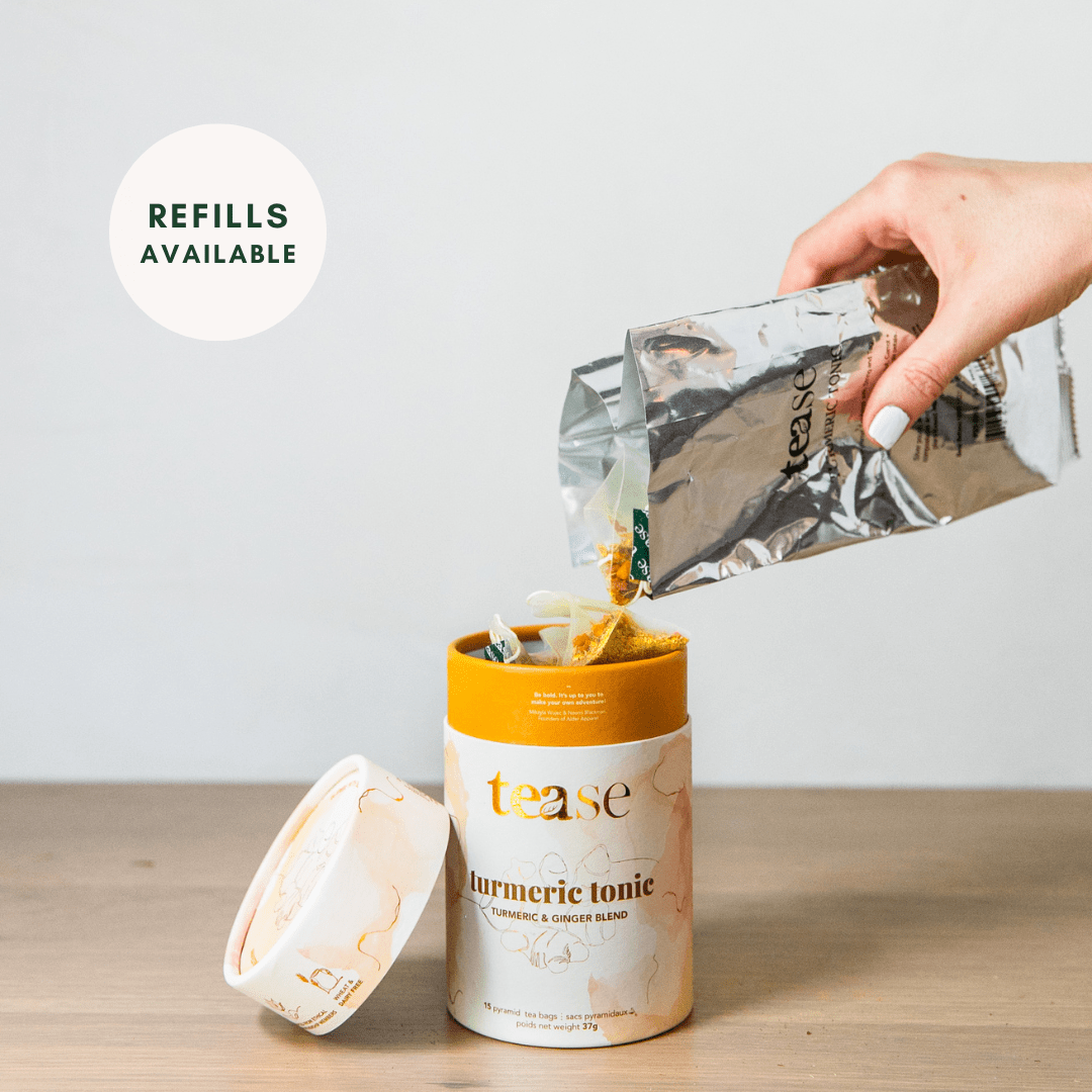 Tease Wellness Turmeric Tonic tea blend in yellow and white tube with loose powder refill being poured from silver pouch.