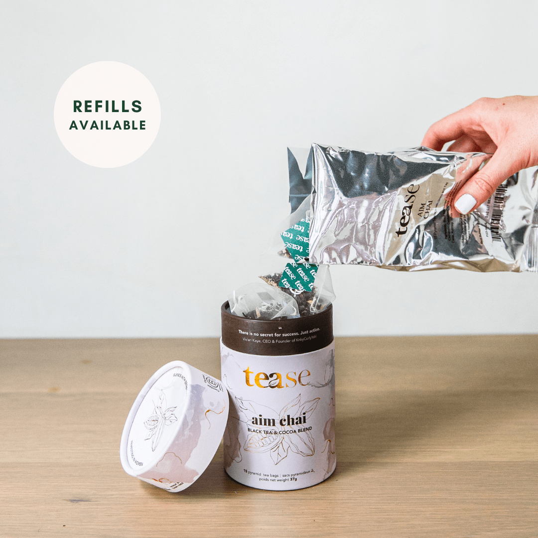Tease Wellness Aim Chai tea blend in white tube packaging with cinnamon and spices, refill pouch being poured in.