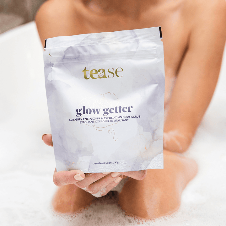 Tease Wellness Glow Getter Earl Grey Body Scrub in white resealable pouch with gold and purple text, calming citrus blend.