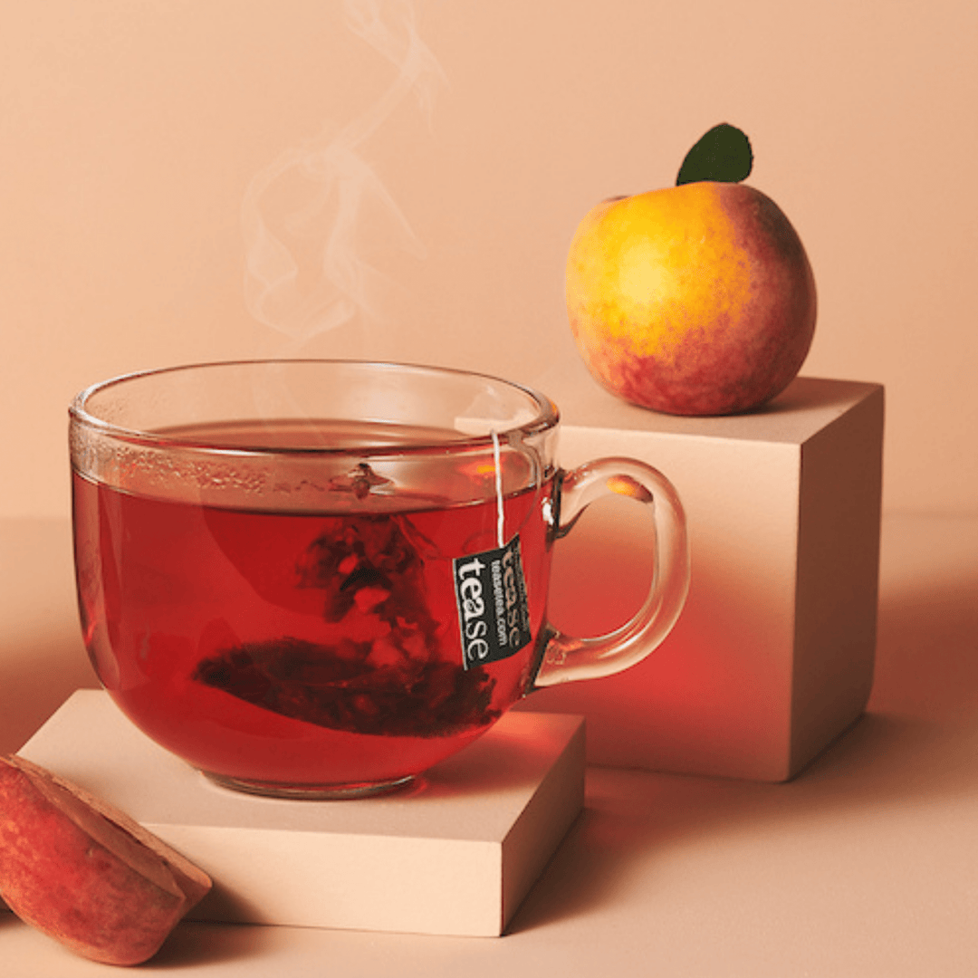 Tease Wellness Peach, Please Refill tea blend in clear glass cup with peach and tea bag tag on soft peach background.
